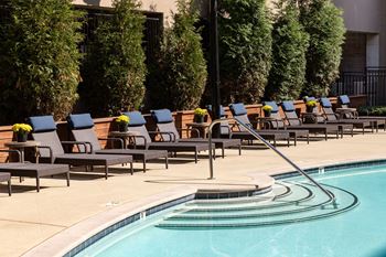 A pool with a slide and chairs around it.